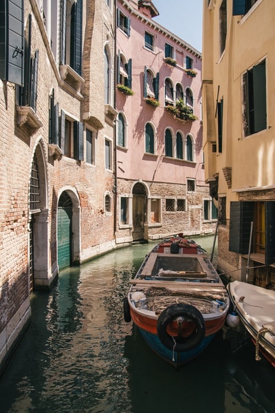 During the day, brown ship sailing on the river between concrete buildings
